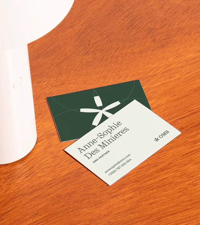 Forest-green and cream business cards stacked on warm wood, minimal, corporate-clean, earthy