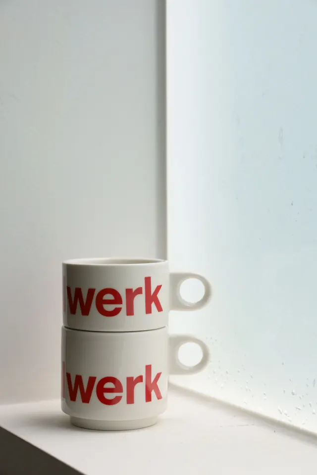werk red-type ceramic mugs on windowsill, minimal, photographic, light