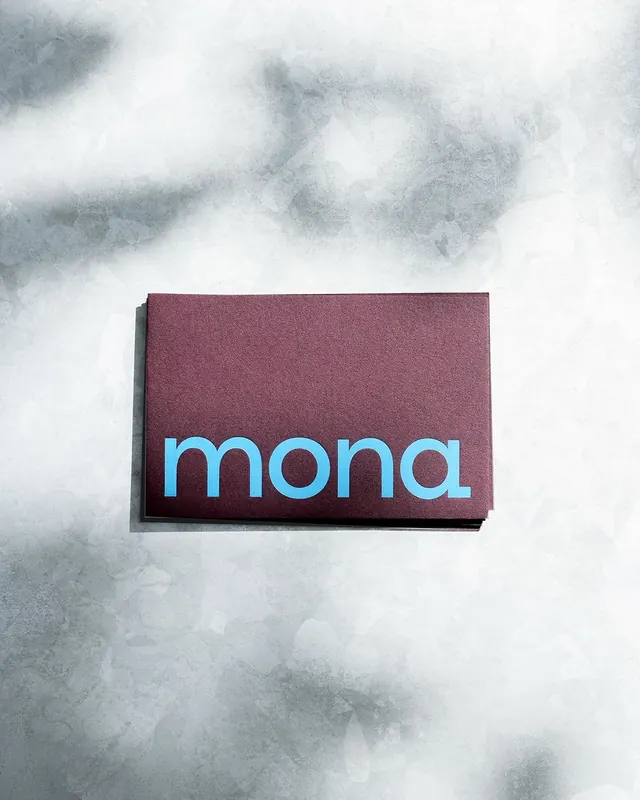 mona business cards: sky-blue lowercase wordmark on plum stock, minimal, editorial, muted