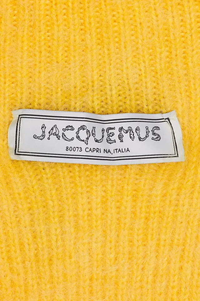Woven garment label on yellow knit, minimal, photographic, vibrant