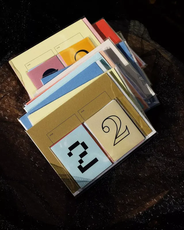 Fanned stack of sleeved pastel print cards, editorial, photographic, muted