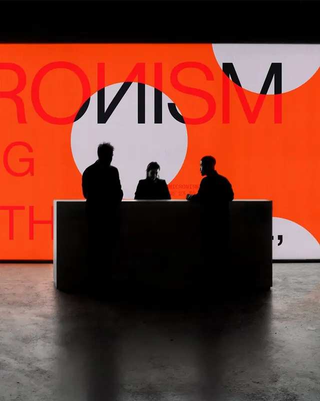 Silhouettes against orange exhibition wall, editorial, geometric, dark