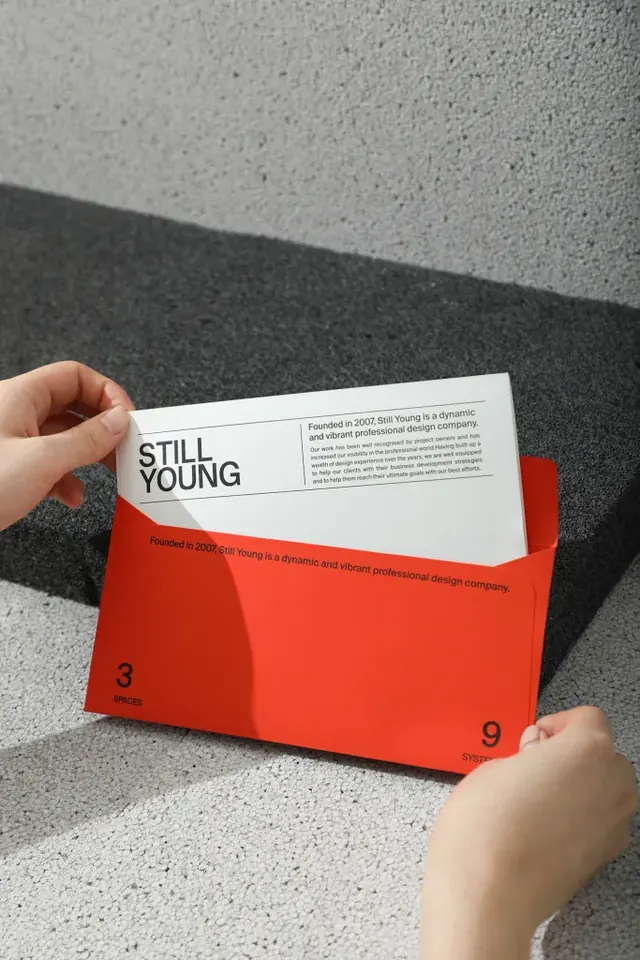 Red editorial envelope with 'Still Young' card insert, minimal, editorial, light