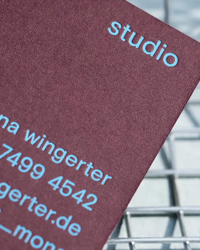 Maroon matte business card with light blue typography, minimal, corporate-clean, light