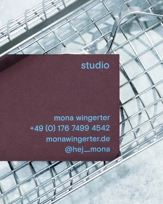 Muted plum business card on industrial metallic backdrop, minimal, corporate-clean, dark
