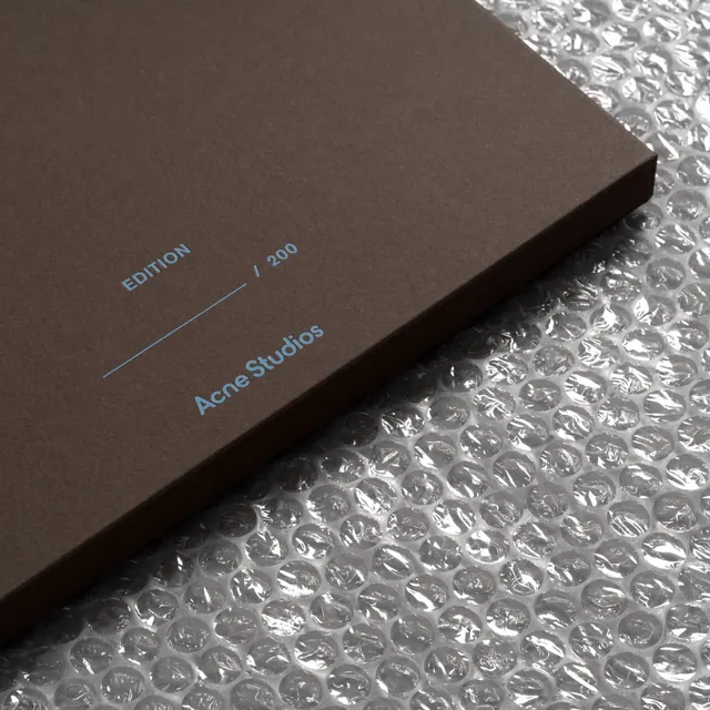 Acne Studios luxury edition box with blue foil accent, minimal, earthy