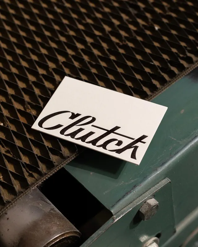 Clutch script card on laser bed, minimal, photographic, muted