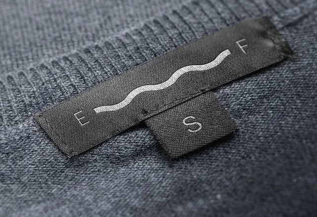 Eas Fors woven labels on knitwear, minimal, photographic, dark