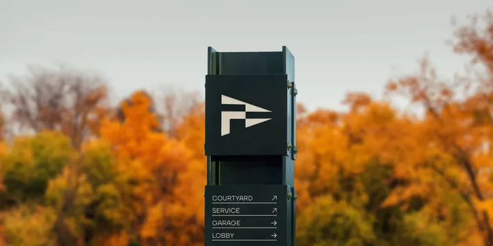 Fenway Center monolith wayfinding sign in autumn trees, minimal, architectural, dark