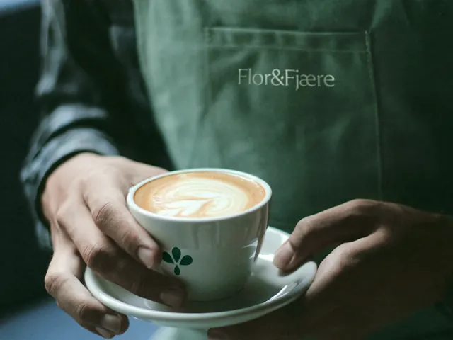 Flor and Fjaere apron and branded coffee cup, minimal, photographic, dark