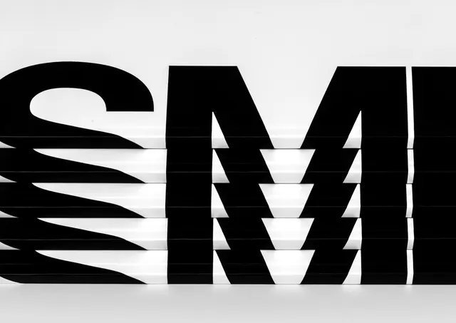 Stacked books with supergraphic SM spine type, minimal, photographic, monochrome