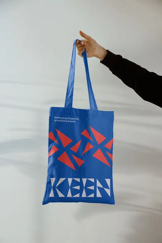 KEEN tote bag held against a white wall, photographic, geometric, vibrant