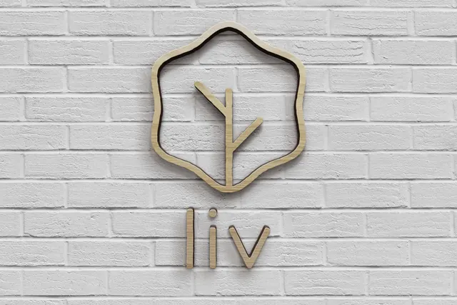 Liv Salad logo cut from birch ply on white brick, minimal, organic, light