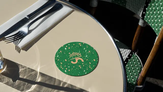 Myrth terrazzo coaster on a sunlit cafe table, photographic, illustrated, warm