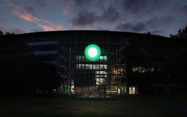 one.nz illuminated orb on a building facade at dusk, architectural, photographic, dark