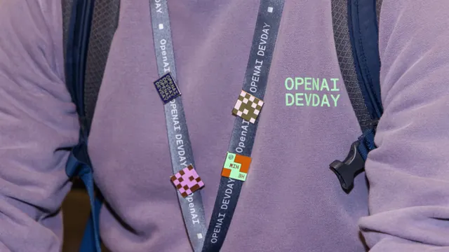 OpenAI DevDay lanyard and enamel pins on attendee, photographic, minimal, muted