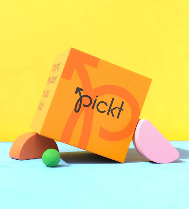 Pickt orange delivery box on pastel props, photographic, playful, vibrant
