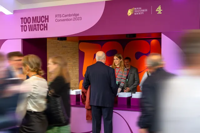 Magenta registration desk with curved brand fascia and orange lettering, typographic, geometric, vibrant