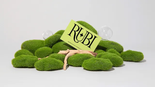 Chartreuse Rubi business card propped on a bed of moss, minimal, photographic, light
