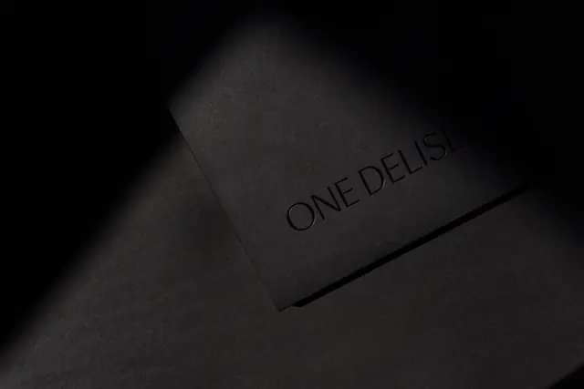 Debossed ONE DELISLE black card, minimal, luxury, dark