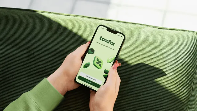 Taxfix app splash screen in hand on green corduroy, minimal, photographic, warm