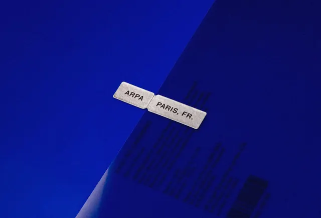ARPA silver tab on cobalt sleeve, minimal, swiss, cool