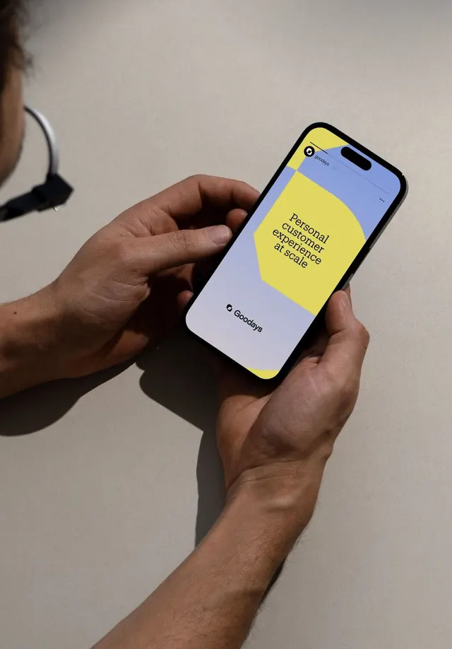 Goodaye app mobile UI mockup held in hands, minimal, flat, vibrant