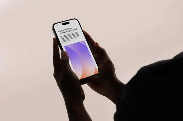 Hand holding phone with purple-to-orange gradient UI screen, minimal, photographic, light