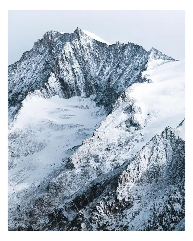 Snow-covered alpine mountain range in cool light, photographic, light