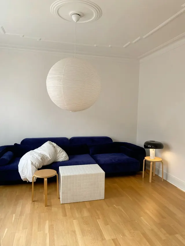Monochromatic interior with navy sofa and sculptural pendant, minimal, organic, light