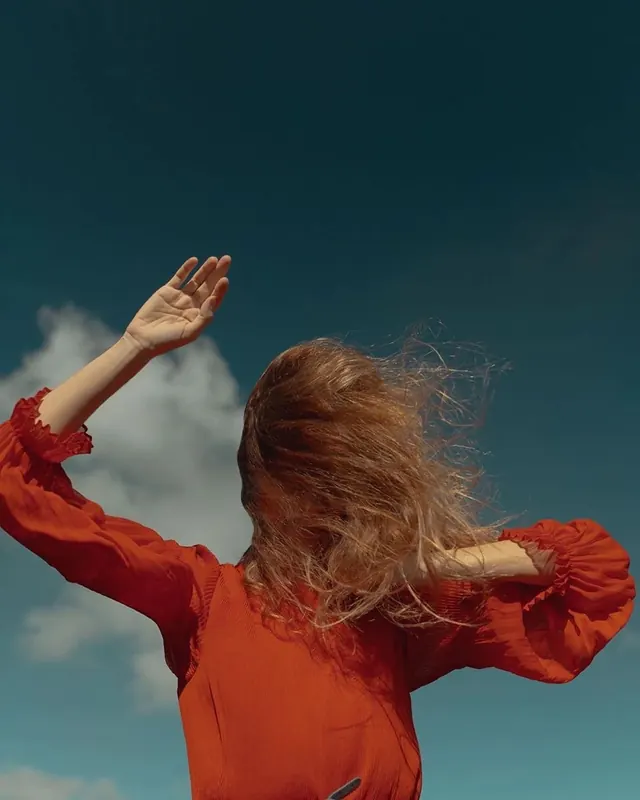Woman in Red Dress Against Blue Sky, photographic, organic, vibrant