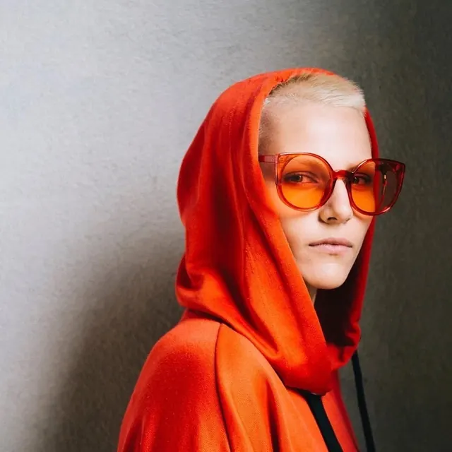 Person in Orange Hoodie with Sunglasses, photographic, minimal, vibrant
