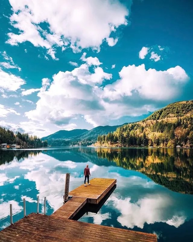 Person Standing on Wooden Dock in Mountain Lake, photographic, organic, vibrant