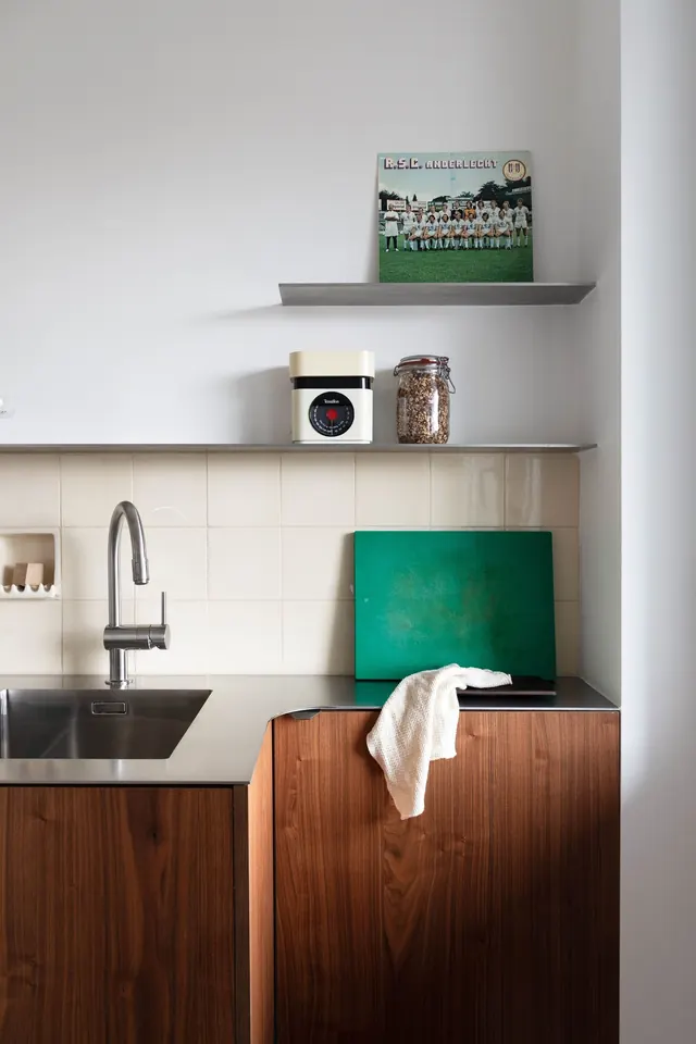 Modern kitchen with walnut cabinetry and green accent, corporate-clean, minimal, warm