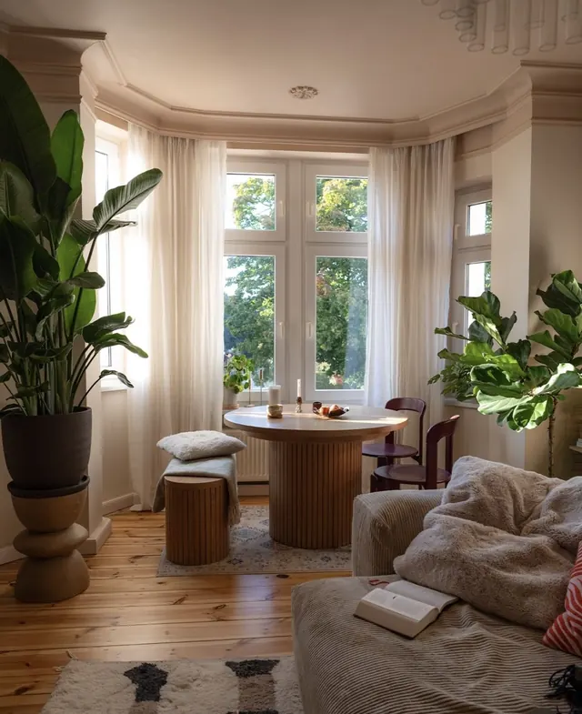 Sunlit living room with curved window and ribbed furniture, photographic, organic, warm