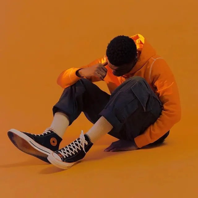 Person in Orange Hoodie and Sneakers, photographic, minimal, vibrant