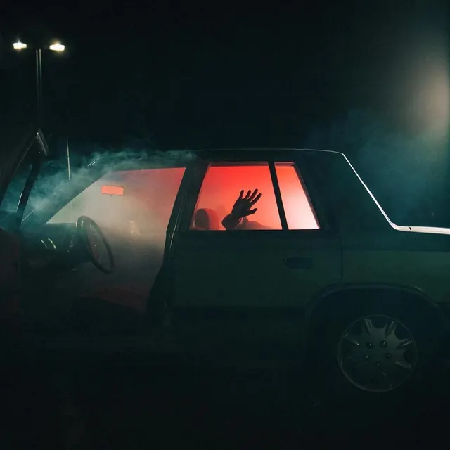 Red-lit car interior with hand pressed to window at night, photographic, cinematic, dark
