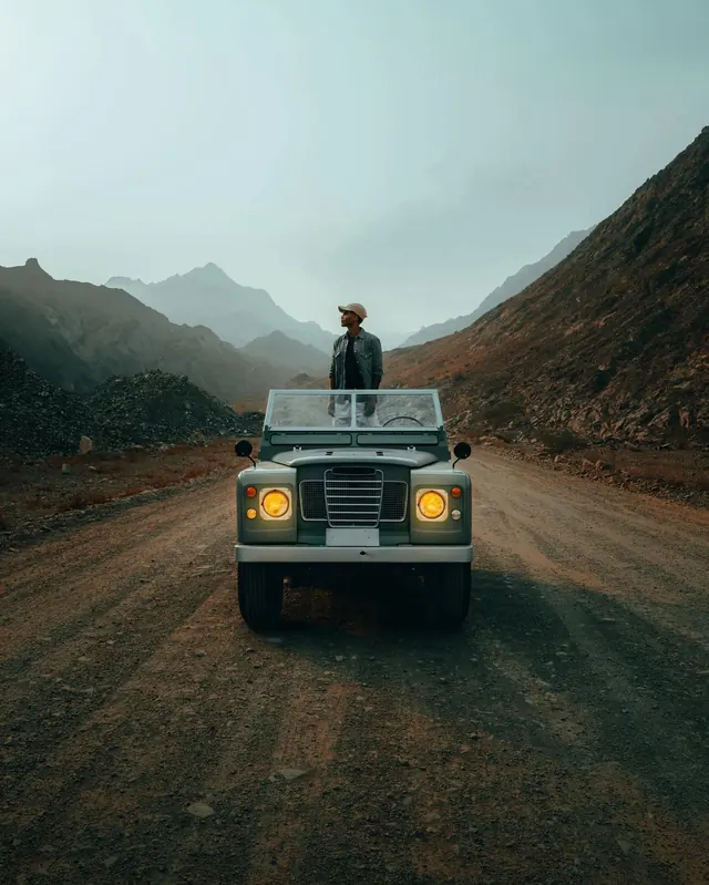 Man Standing on Vintage Truck in Mountains, photographic, minimal, muted
