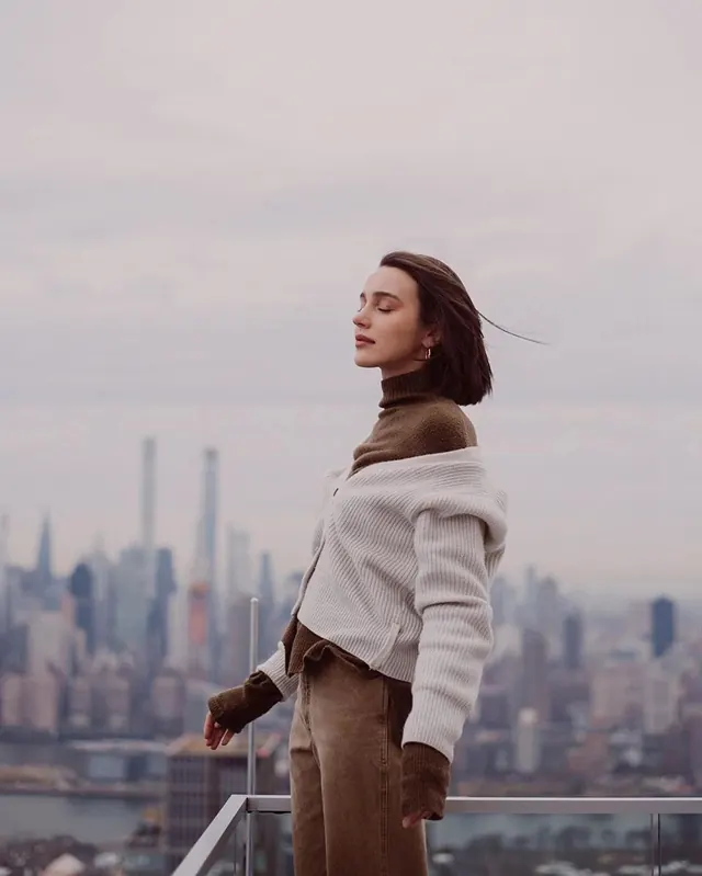 Woman in White Coat Overlooking Cityscape, photographic, minimal, muted