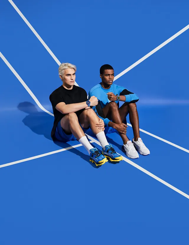Two Men Sitting on a Blue Surface, photographic, minimal, vibrant