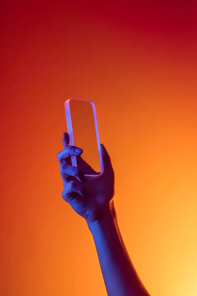 Hand Holding Smartphone with Orange Gradient Background, minimal, photographic, vibrant