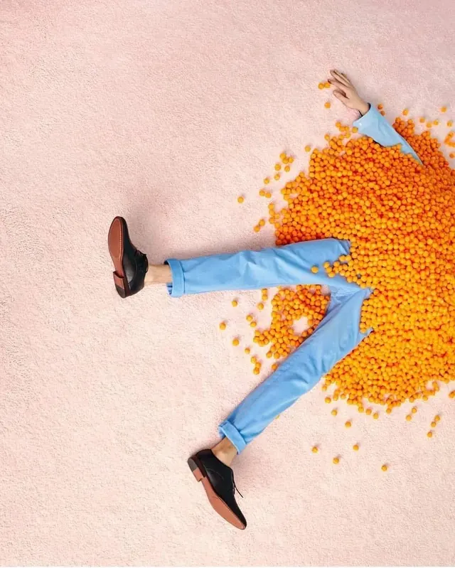 Person Lying in Orange Beans, minimal, playful, vibrant