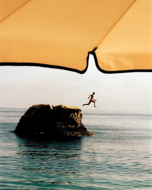 Person Jumping Over Rock in Ocean, minimal, photographic, warm