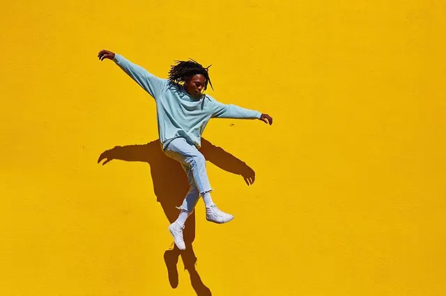 Person in Blue Jumpsuit on Yellow Background, minimal, playful, vibrant
