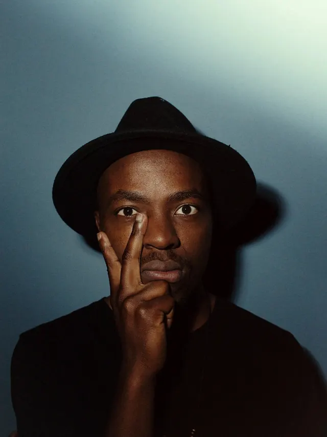 Man in Hat with Finger to Lips, photographic, minimal, dark