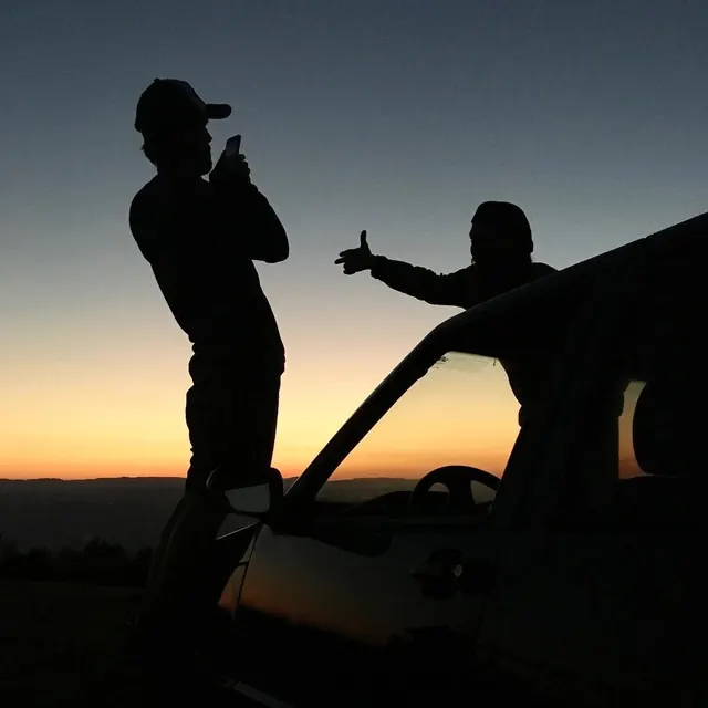 Silhouette of Two People in a Vehicle at Sunset, photographic, high-contrast
