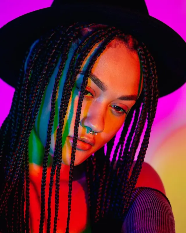 Portrait of a Woman with Braids and Neon Lighting, photographic, maximalist, vibrant