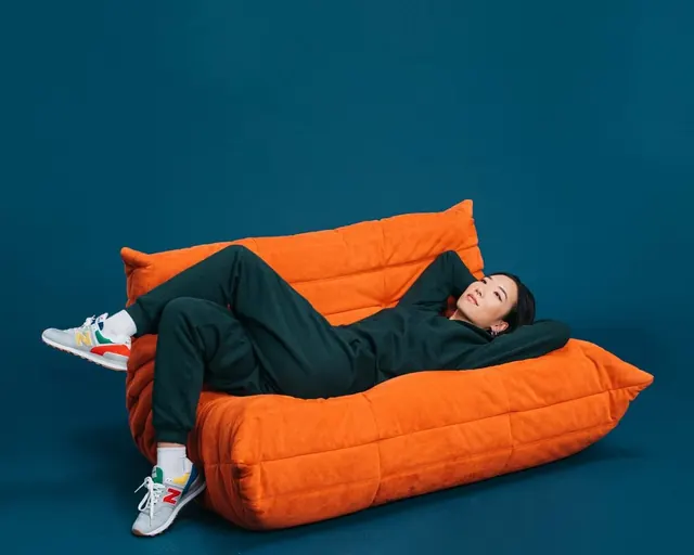 Man Relaxing on Orange Bean Bag Chair, minimal, photographic, vibrant