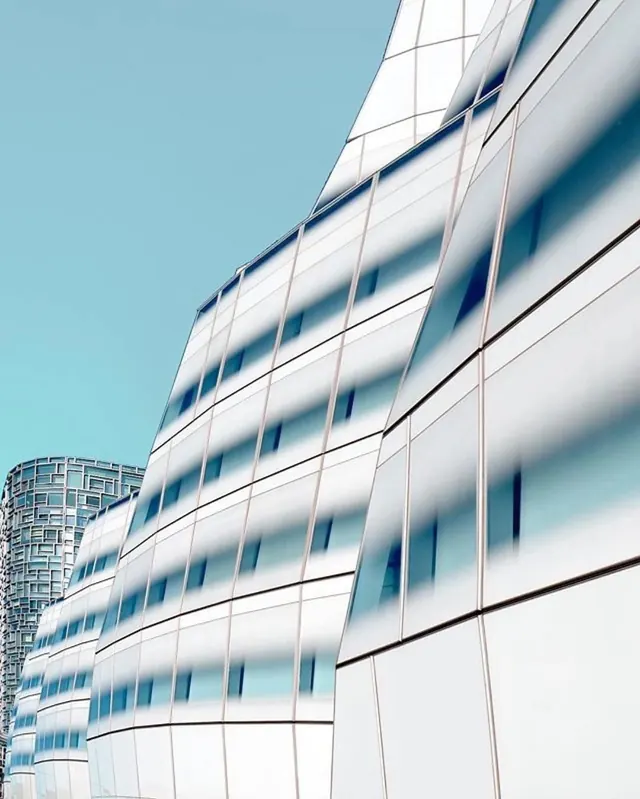 Curved white glass facade against a teal sky, photographic, architectural, light