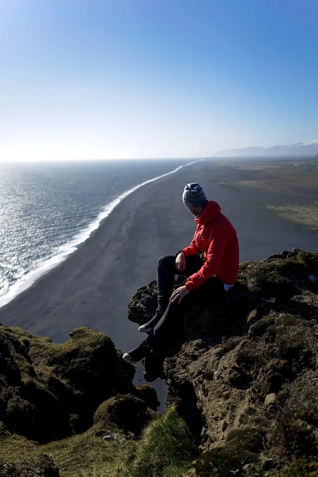 Man Sitting on Cliff Over Beach, photographic, organic, vibrant